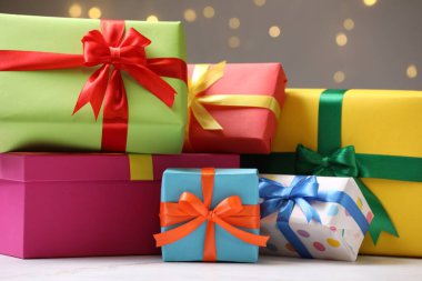 Beyaz masadaki güzel hediye kutuları gri arka planda, bokeh ışıkları, yakın plan.