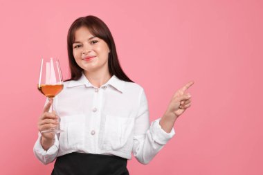 Pembe arka planda beyaz şarap kadehi olan profesyonel şarap garsonu.