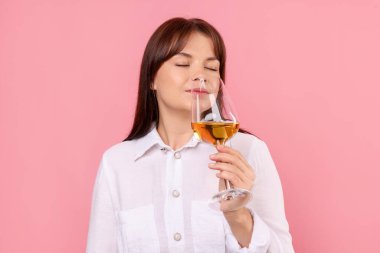 Profesyonel şarap garsonu pembe arka planda beyaz şarap tadıyor.