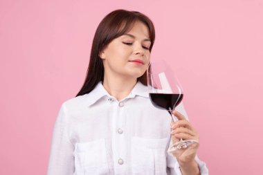 Profesyonel şarap garsonu pembe arka planda kırmızı şarap tadıyor.