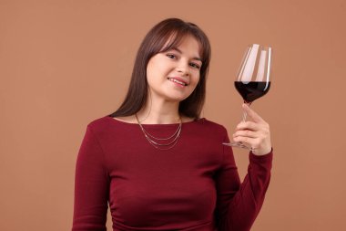 Soluk kahverengi arka planda kırmızı şarap kadehi olan profesyonel şarap garsonu.