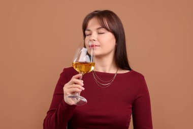 Profesyonel şarap garsonu açık kahverengi arka planda beyaz şarap tadıyor.