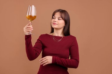 Soluk kahverengi arka planda beyaz şarap kadehi olan profesyonel şarap garsonu.