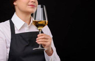 Siyah arka planda kırmızı şarap kadehi olan profesyonel şarap garsonu, yakın plan. Metin için boşluk