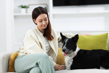 Evdeki kanepesinde Collie köpeği olan bir kadın.