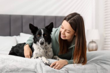 Evde yatağında Collie köpeği olan bir kadın.