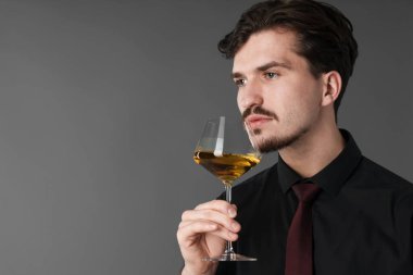 Profesyonel şarap garsonu gri arka planda beyaz şarap tadıyor. Metin için boşluk