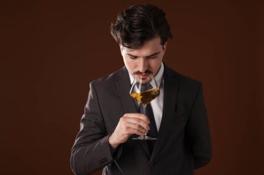 Profesyonel şarap garsonu kahverengi arka planda beyaz şarap tadıyor.
