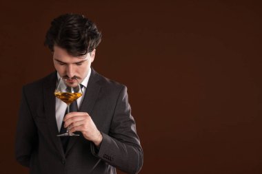 Profesyonel şarap garsonu kahverengi arka planda beyaz şarap tadıyor. Metin için boşluk