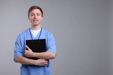 Gri arkaplanda panosu olan tıbbi asistanın portresi, metin için boşluk