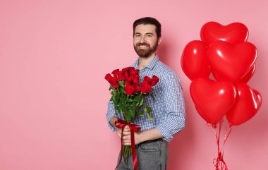 Sevgililer Günü. Buketi ve pembe arka planda kalp şeklinde balonları olan adam. Metin için boşluk