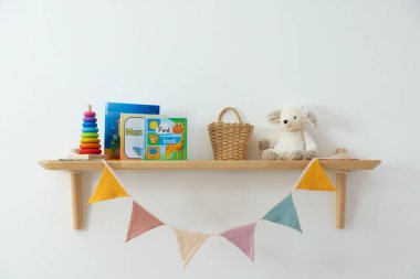 Farklı oyuncakları ve açık renkli kitapları olan raflar.