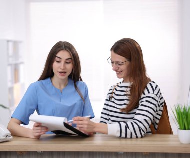 Klinikteki resepsiyonda hastaya yardım eden tıbbi asistan