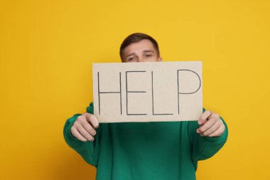 Man holding sign with word Help on yellow background