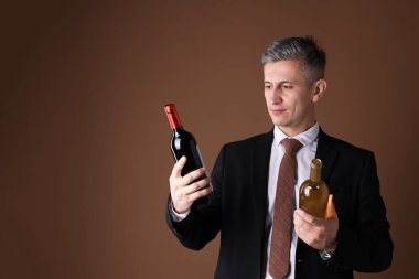 Kahverengi arka planda şarap şişeleri olan profesyonel şarap garsonu.