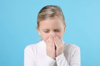 Açık mavi arka planda burnu akan küçük bir kız. Soğuk Semptom