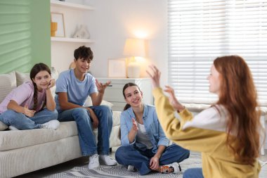 Evde sessiz sinema oynayan bir grup genç.