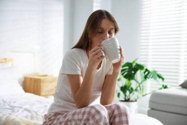 Evdeki yatakta bir fincan aromatik kahveyle güzel bir kadın.