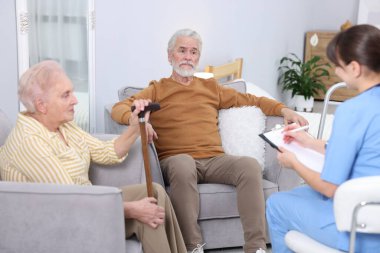 Bakım görevlisi yaşlı kadın ve erkeğe huzurevinde iyi olup olmadıklarını soruyor.