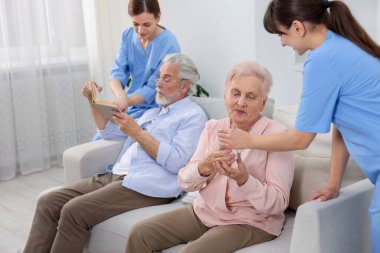 Bakım işçileri huzurevindeki yaşlı adam ve kadına yardım ediyor.