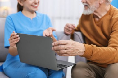 Bakım işçisi, huzurevinde dizüstü bilgisayar kullanmayı öğretiyor.