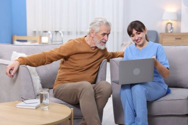 Bakıcı, huzurevinde dizüstü bilgisayar kullanmayı öğretiyor.