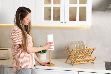 Mutfaktaki beyaz mermer tezgahta kağıt havlu kullanan bir kadın.