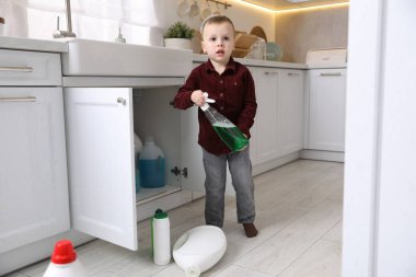 Evde çocuk güvenliği. Küçük çocuk mutfakta temizlik ürünleriyle oynuyor.