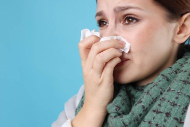 Açık mavi arka planda burnu akan bir kadın, yakın plan ve mesaj için yeri var. Soğuk Semptom