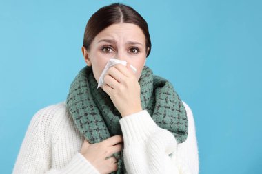 Açık mavi arka planda burnu akan bir kadın. Soğuk Semptom