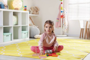 Oyun odasındaki küçük kız piramit oyuncağıyla oynuyor.