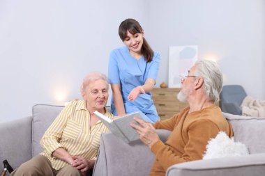 Yaşlı adam, kadın ve bakıcı huzurevinde kitabı tartışıyorlar.