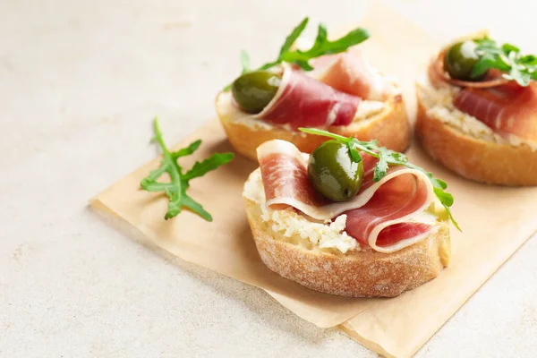 Krem peynirli, jambonlu, yeşil zeytinli ve roka soslu nefis bruschetalar, yakın plan. Metin için boşluk