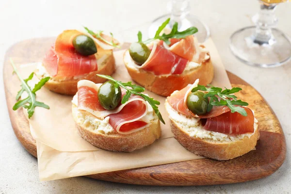 Krem peynirli nefis bruschettalar, prosciutto, yeşil zeytin ve roka masada, yakın plan.