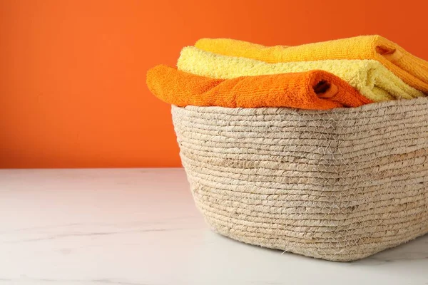 Çamaşır sepetinin içinde turuncu duvarın yanındaki ışıklı masada havlular var. Yakın plan. Metin için boşluk