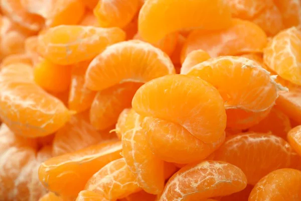 Arka plan olarak birçok olgun soyulmuş mandalina, yakın plan