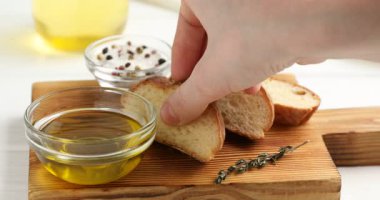Masada bir dilim ekmeği zeytinyağına batıran kadın, yakın plan.