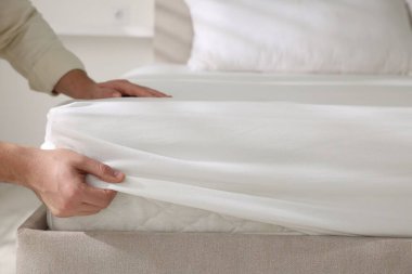 Adam yatak çarşaflarını kapalı bir yere koyuyor.