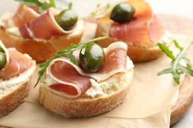 Krem peynirli nefis bruschettalar, prosciutto, yeşil zeytin ve roka masada, yakın plan.