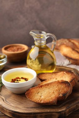 Izgara ekmek dilimleri, zeytinyağı ve baharatlar ahşap masada, yakın plan.
