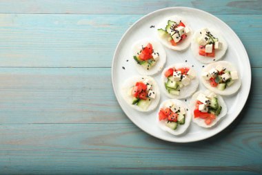 Sebzeli lezzetli pirinç kağıdı cipsi, beyaz peynir ve açık mavi ahşap masa üzerinde siyah susam tohumları, üst manzara. Metin için boşluk