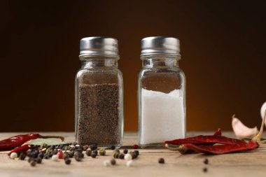 Tuz ve karabiber karıştırıcıları ahşap masa üzerinde kahverengi gradyan arka plan, yakın çekim