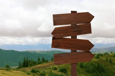 Dağların farklı yönlerini gösteren okları olan tahta tabela direği.