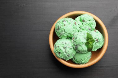 Siyah ahşap masadaki kasede nefis naneli çikolata parçalı dondurma. Metin için boşluk