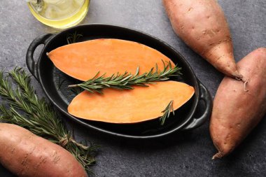 Çiğ patates, biberiye ve yağ siyah masada, düz yerde.