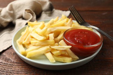 Tahta masada ketçapla servis edilen leziz patates kızartmaları, yakın plan.
