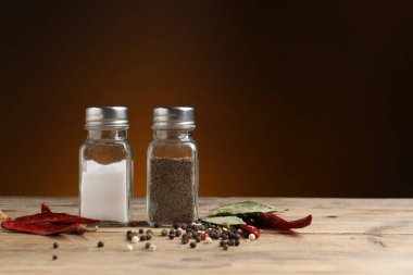 Tuz ve biber karıştırıcılar ahşap masa üzerinde kahverengi gradyan arkaplan, metin için boşluk