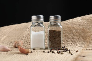 Siyah arka planda baharatlı tuzluk ve biber.