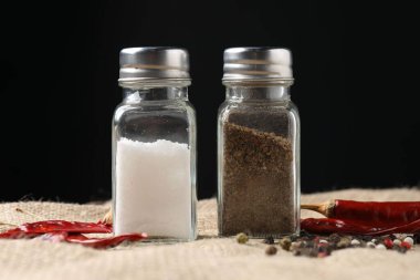 Siyah arka plana karşı baharatlı tuzluk ve biber karıştırıcılar, yakın plan.