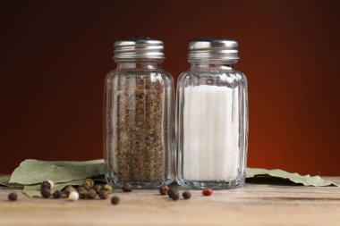 Ahşap masada baharatlı tuzluk ve biberlikler koyu arka planda, yakın planda.